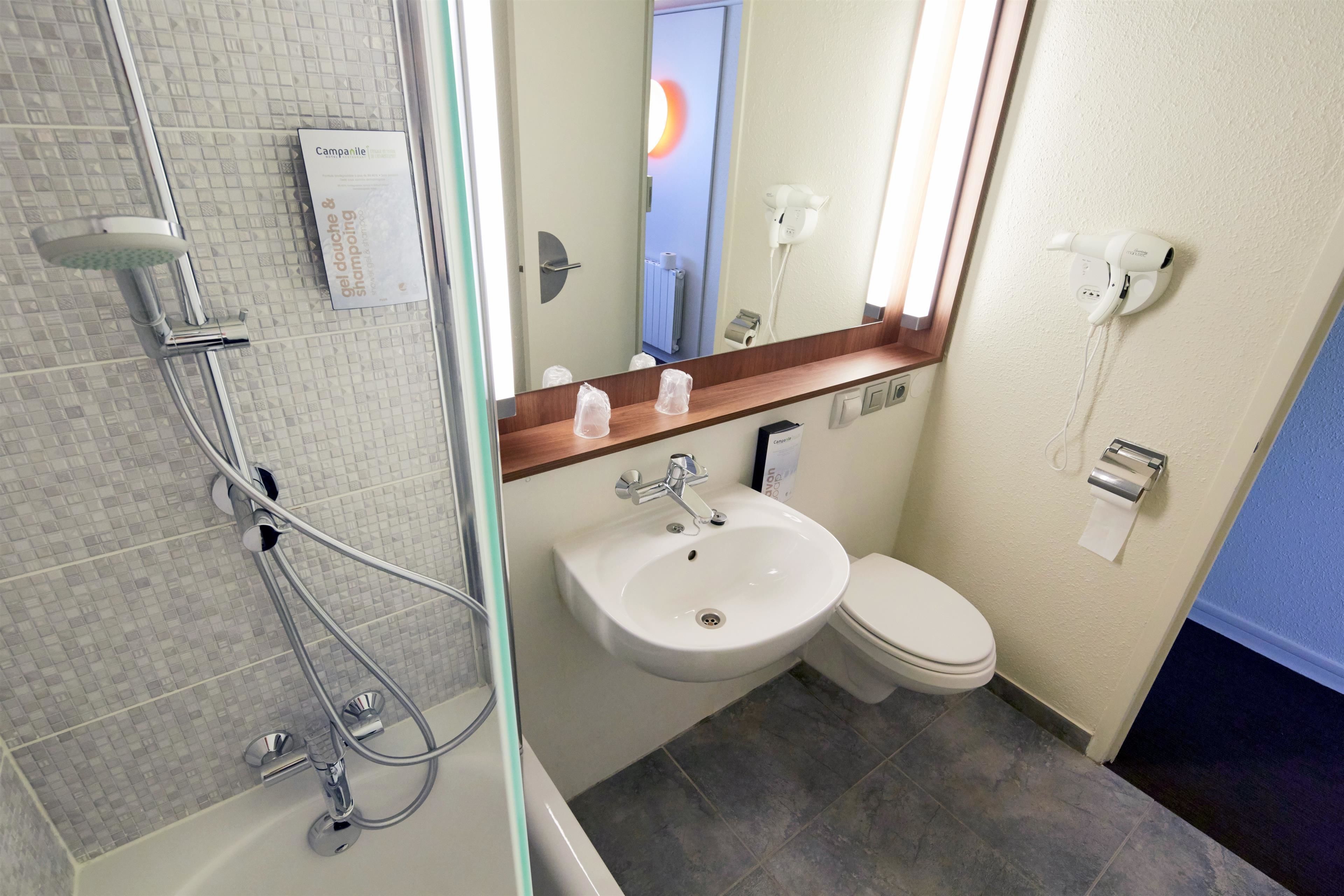 Ein modernes Badezimmer mit einer gläsernen Duschkabine, einem Waschbecken und einer Toilette.