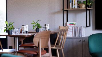 A restaurant interior with a wooden table, chairs, potted plants, and a menu board.