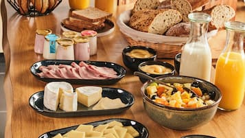 Un bufé de desayuno con diversos quesos, carnes, panes y bebidas.
