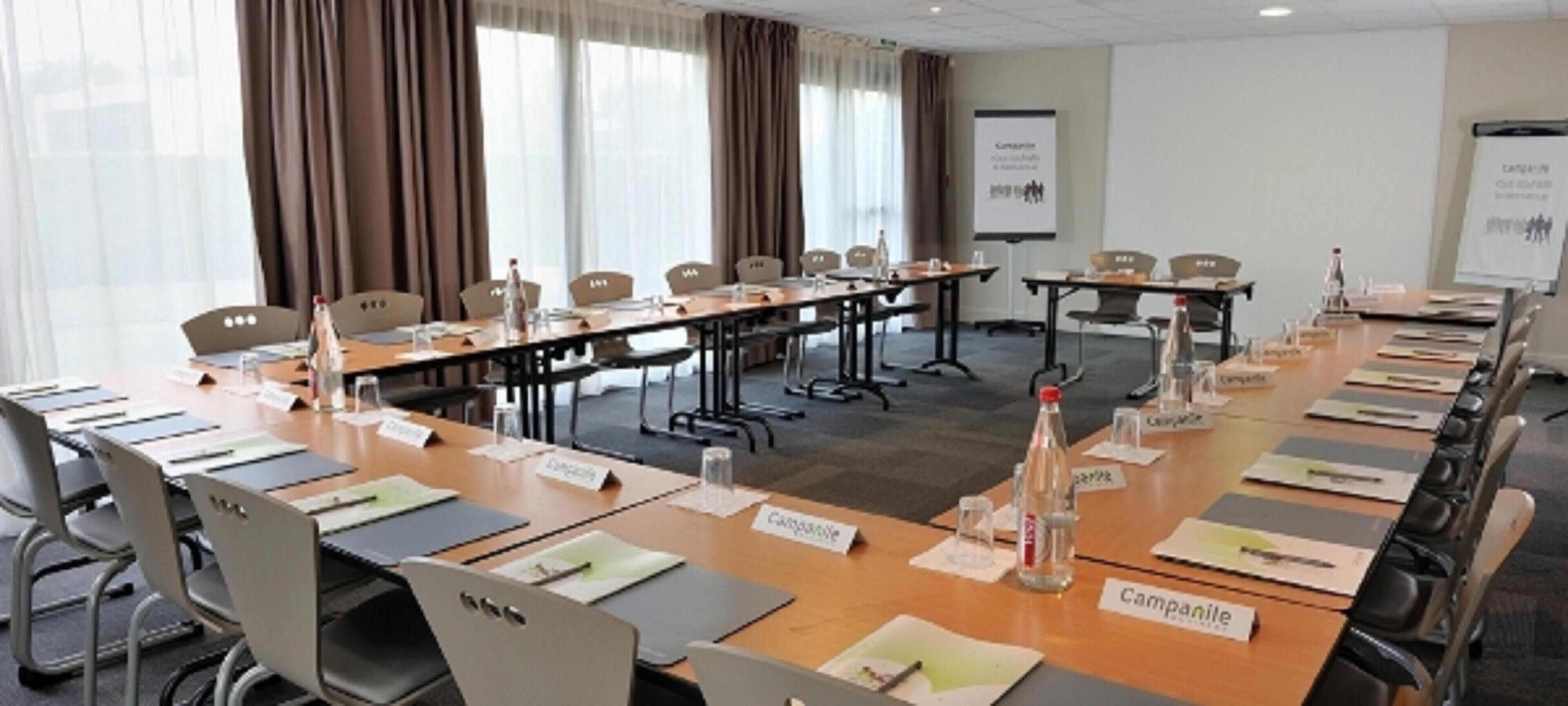 A conference room with multiple tables, name placards, and presentation screens.