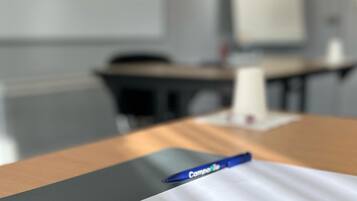 A blurred office setting with a desk, a pen, and a whiteboard in the background.
