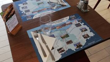 Een eettafel met een kaart van een regio, bestek, een glas en een menukaart.