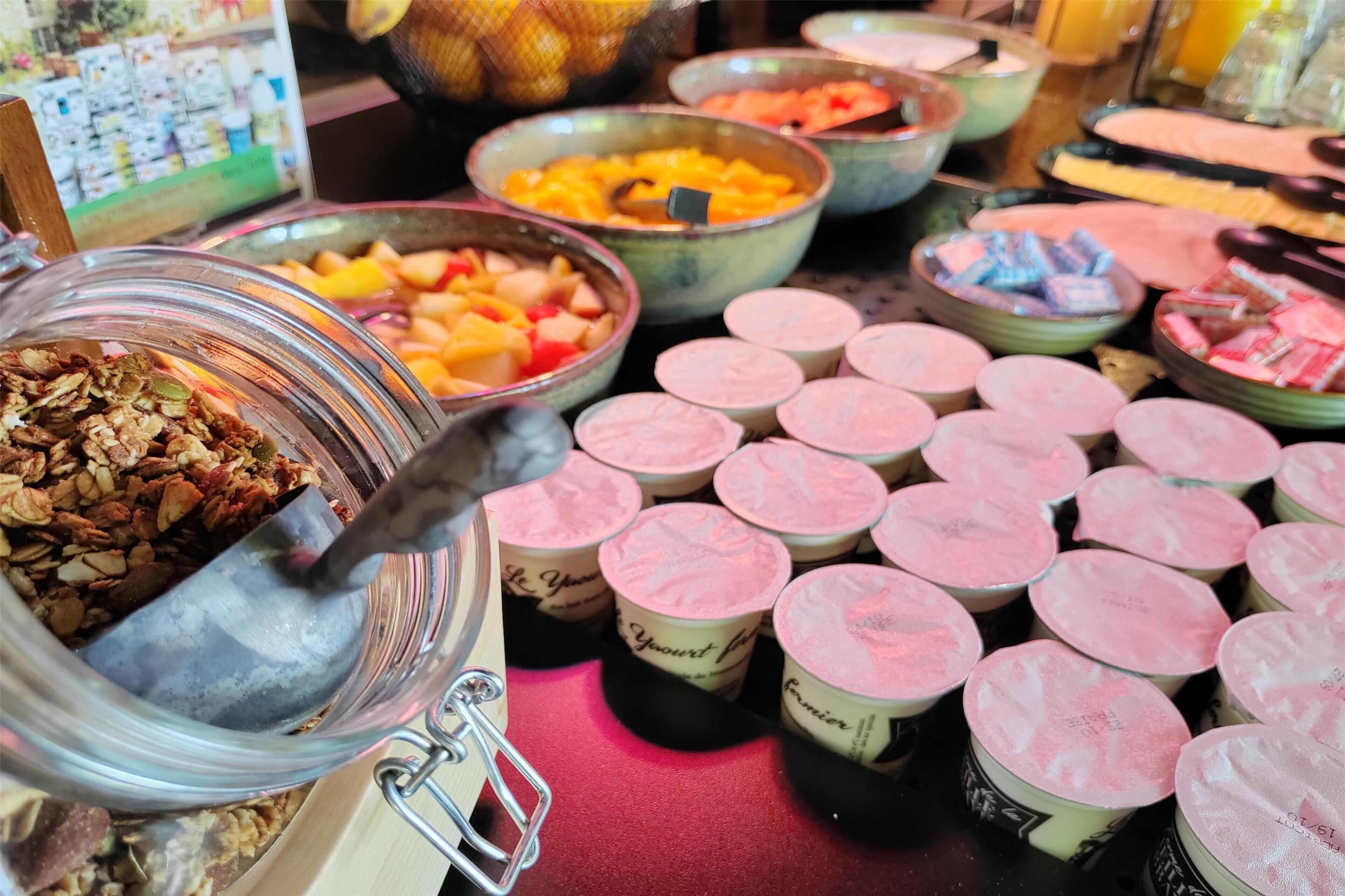 Een ontbijtbuffet met diverse producten zoals fruit, yoghurt en granola.