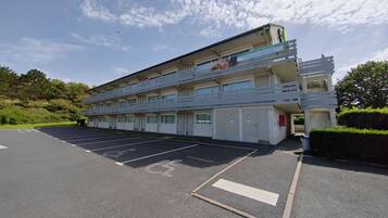A multi-story hotel with a parking lot and a wheelchair-accessible space.