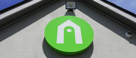 A building with a green circular sign featuring a white house symbol.