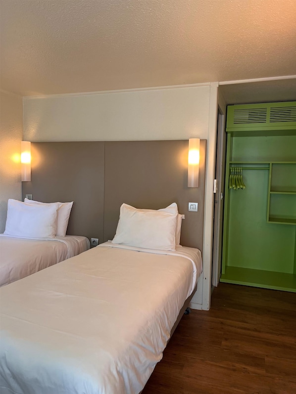 Habitación de hotel con dos camas, una puerta verde y un interruptor de luz en la pared.