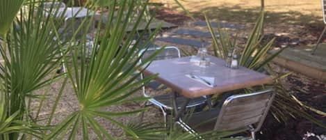 A patio area with a table and chairs, surrounded by potted plants and a gravel ground.