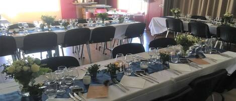 Comedor con varias mesas dispuestas para una comida, cada una con sillas, cubiertos y cristalería.