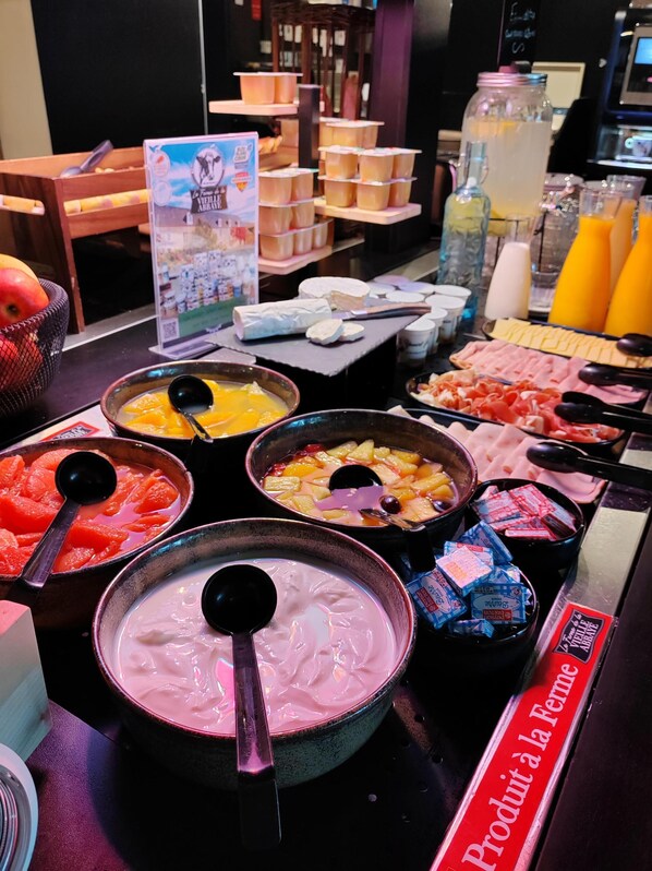 A buffet with various food items including fruits, cheeses, and desserts.