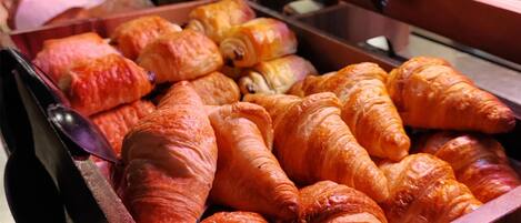 Eine Auswahl an Backwaren, darunter Croissants und andere Gebäcke, ansprechend auf Holztassen angerichtet.