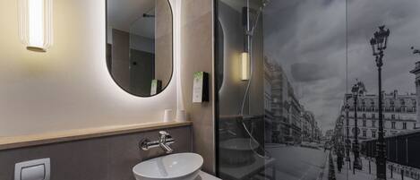 A modern bathroom with a large mirror, a round mirror, a white sink, and a glass shower enclosure.