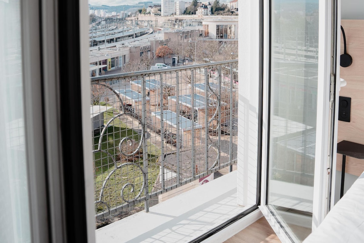 Um apartamento moderno com uma grande janela, vista para a paisagem urbana e varanda com grade de metal.