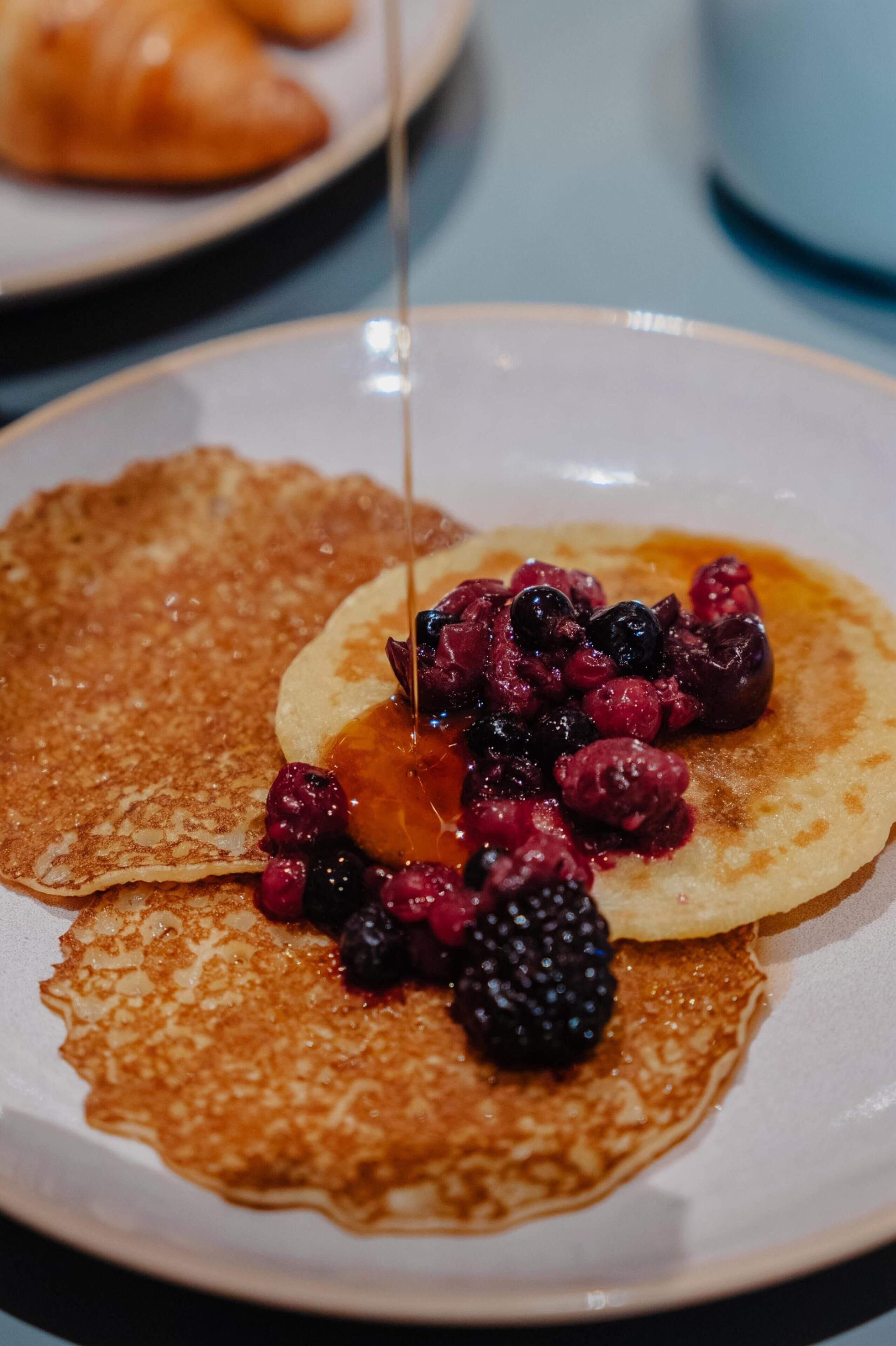 A plate with pancakes topped with berries and syrup.