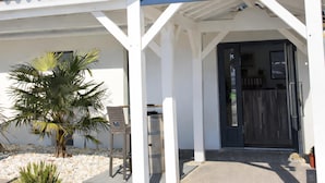 A building with a reception sign, a door, and a small palm tree. - Kyriad Bordeaux - Mérignac Aéroport (Merignac)