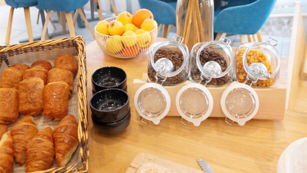 A breakfast buffet with pastries, fruits, coffee, and a decorative vase. - Kyriad Bordeaux - Mérignac Aéroport (Merignac)
