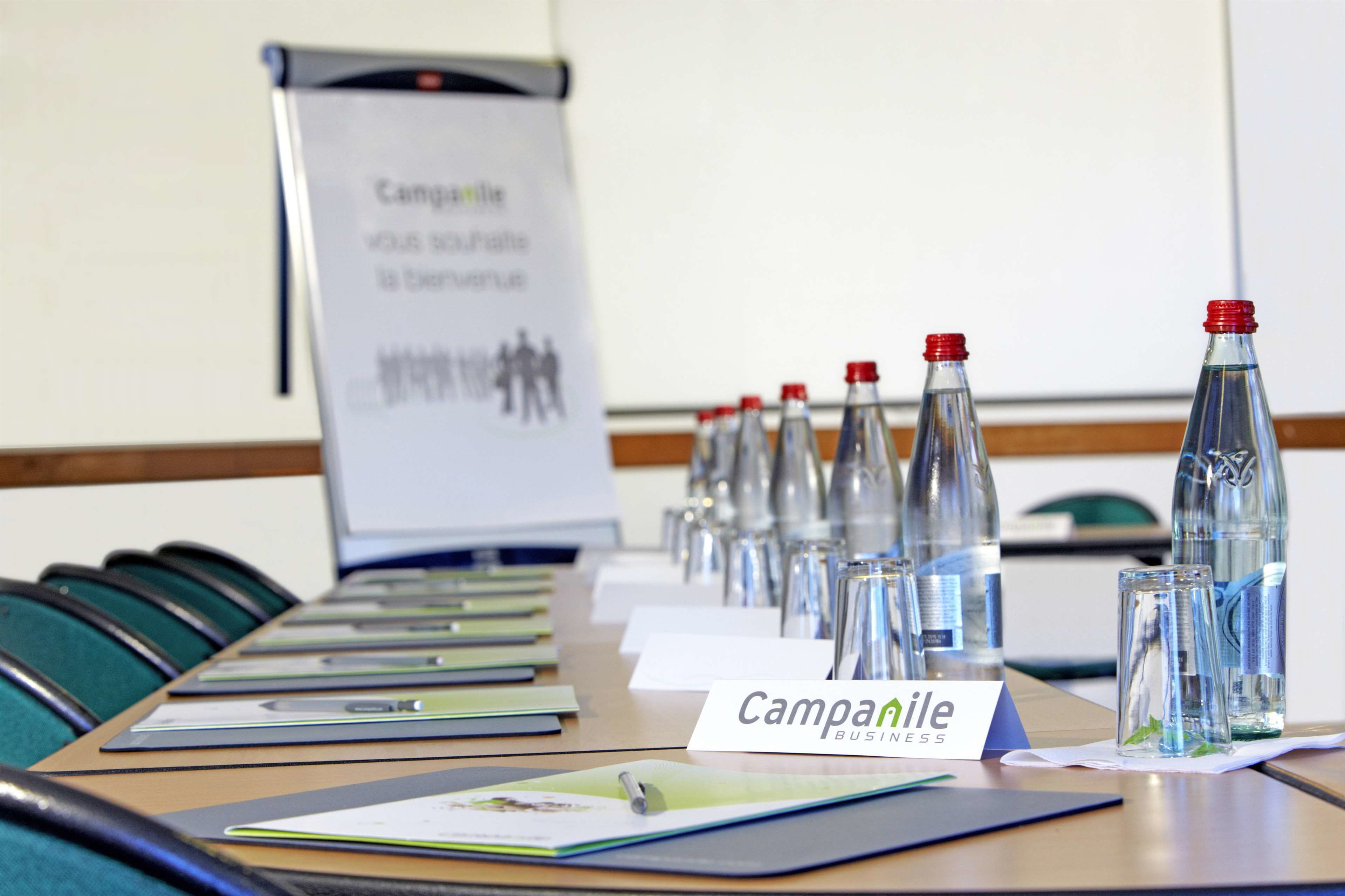 Une table de conférence avec des porte-noms, des bouteilles d’eau et des documents.