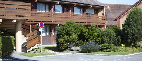 A building with a wooden balcony, a no parking sign, and a wheelchair-accessible parking space.