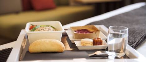 A tray with a bowl of soup, a pastry, a small plate with a cookie, and a glass of water on a bed.
