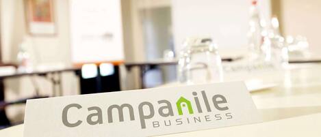 A sign with the text "Campanile Business" in a conference room setting.