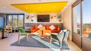 A modern living room with a sofa, chairs, a coffee table, and a TV. - Campanile NATURE - Clermont Ferrand Le Brézet (Clermont-Ferrand)
