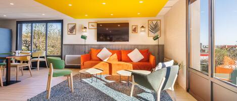 A modern living room with a sofa, chairs, a coffee table, and a TV.