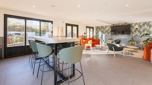 A modern interior with a bar area, seating, and a TV. - Campanile NATURE - Clermont Ferrand Le Brézet (Clermont-Ferrand)
