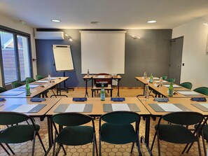 A conference room with tables, chairs, a projector screen, and nameplates. - Campanile Clermont Thiers (Thiers)