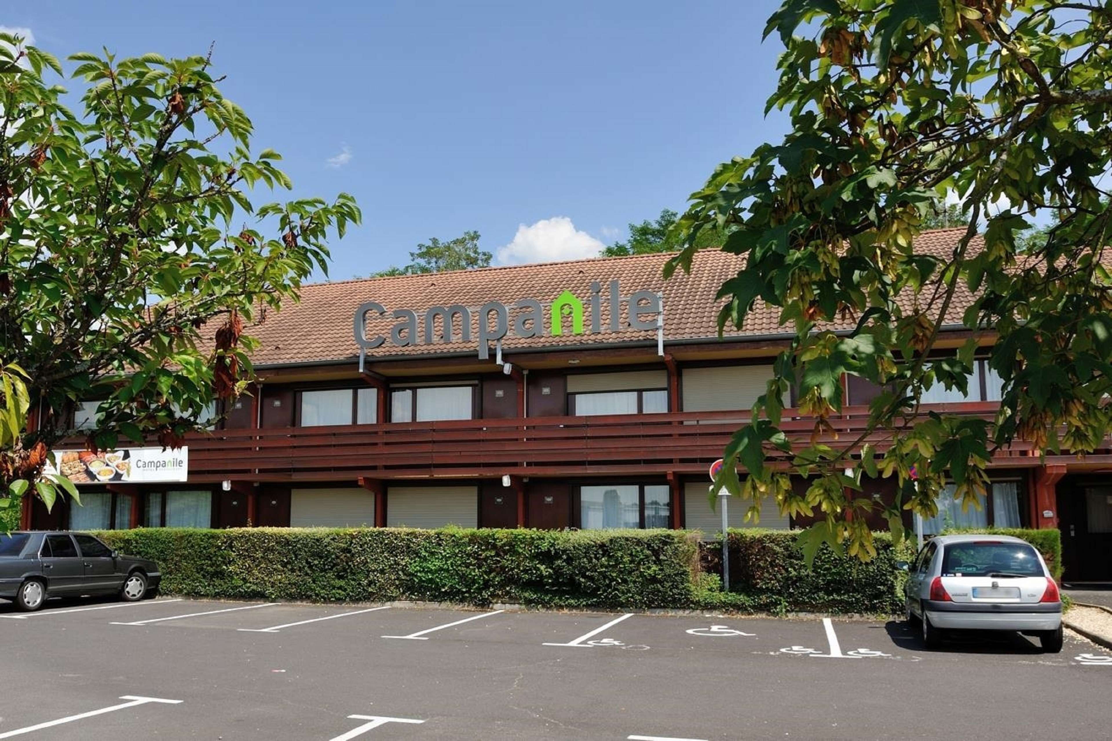 A building with a sign reading "Campanile" and a parking lot with marked spaces.