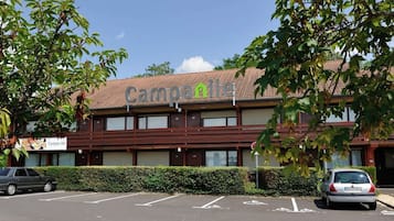 A building with a sign reading "Campanile" and a parking lot with marked spaces.