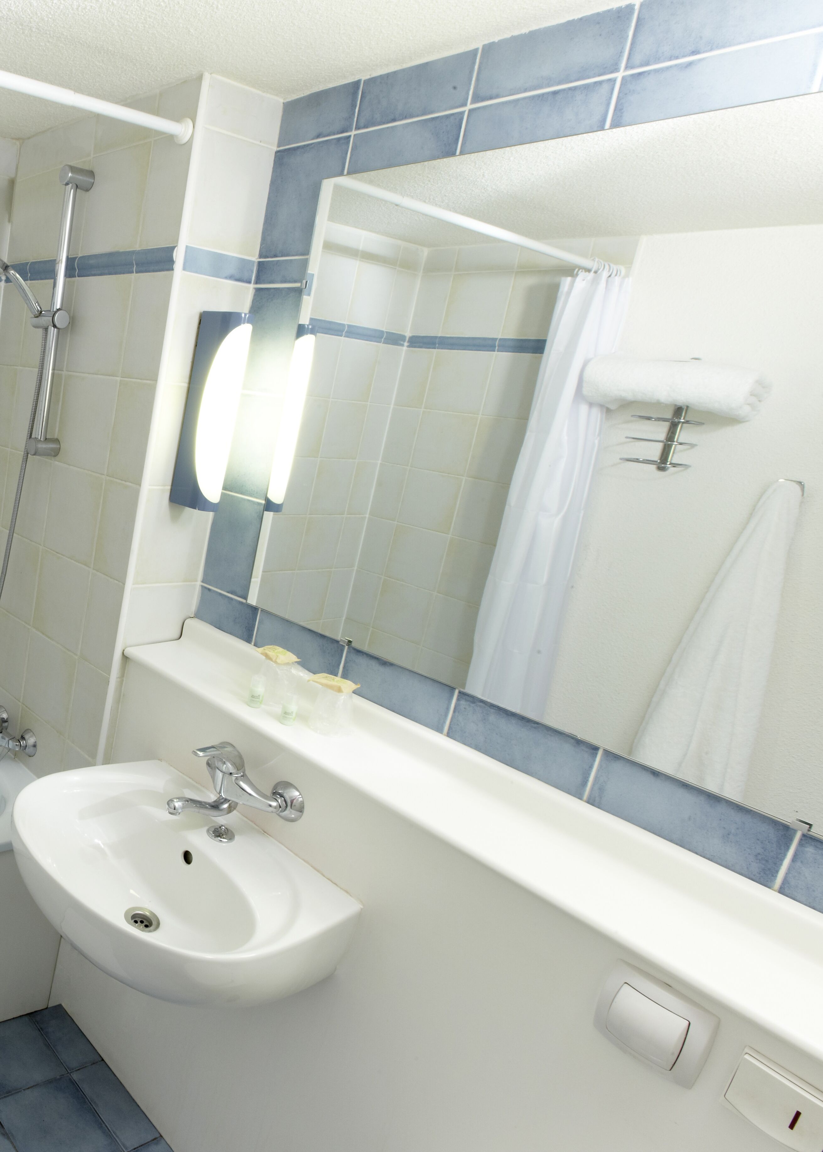 A bathroom with a sink, mirror, and shower.