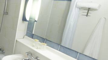 A bathroom with a sink, mirror, and shower.