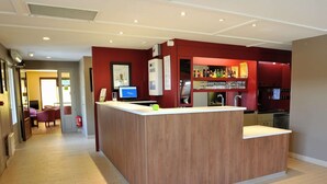 Una cocina moderna con una isla central, una zona de bar con estantes llenos de botellas y un comedor con sillas.
