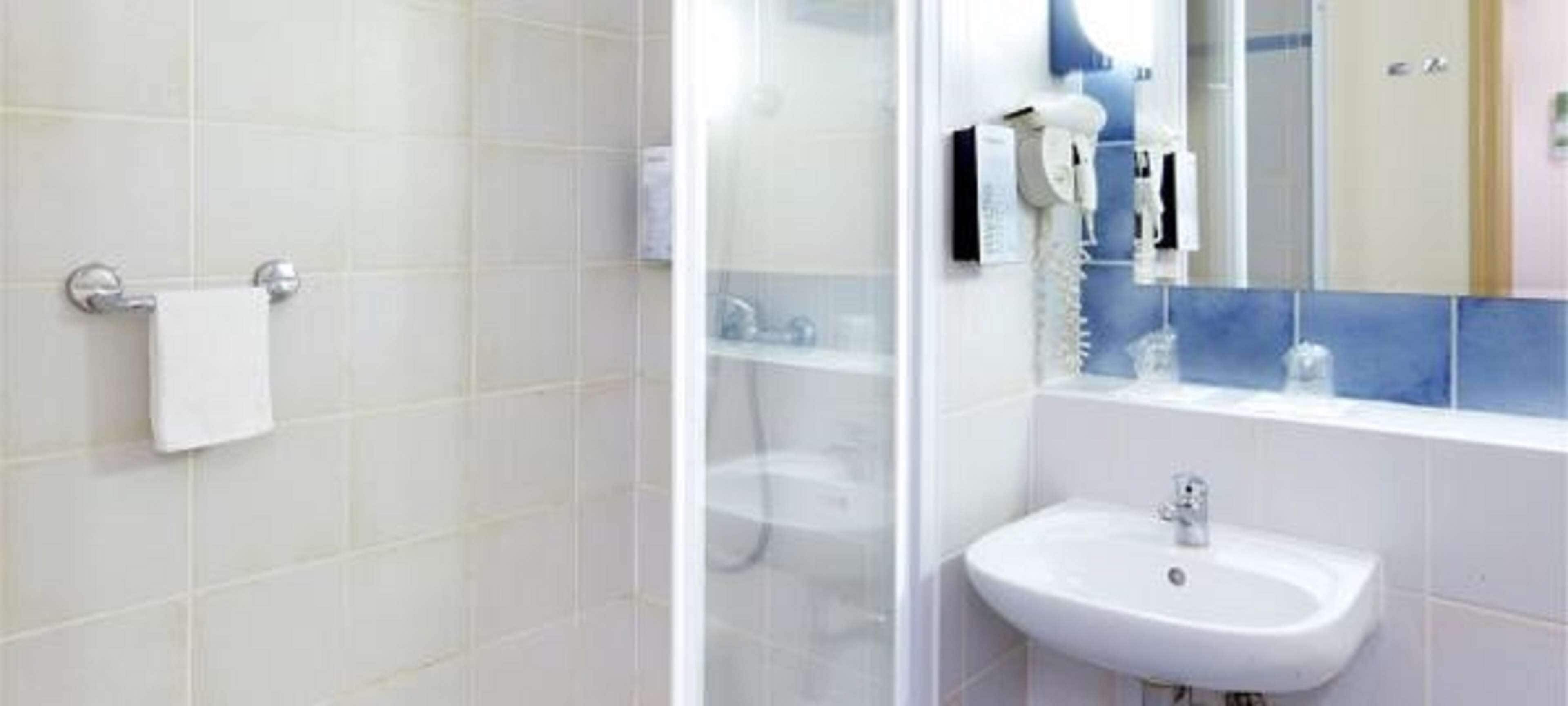 A bathroom with a white sink, a glass shower enclosure, and a towel rack.