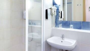 A bathroom with a white sink, a glass shower enclosure, and a towel rack.