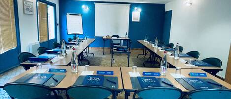 A conference room with tables, chairs, name cards, and water bottles.