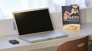 A laptop on a desk with a menu stand beside it.