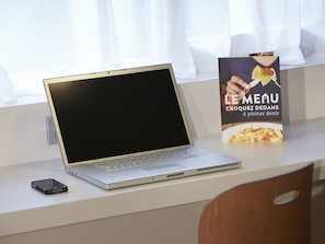 A laptop on a desk with a menu stand beside it.