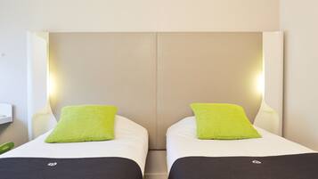 A double room with two beds, each with a green pillow and black bedspread.