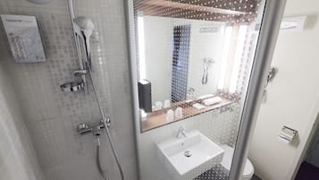 A modern bathroom with a glass shower enclosure, a white sink, and a mirror reflecting the room.