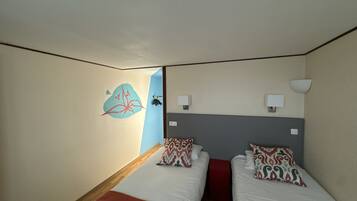 A hotel room with two beds, a red accent wall, and a decorative wall art piece.