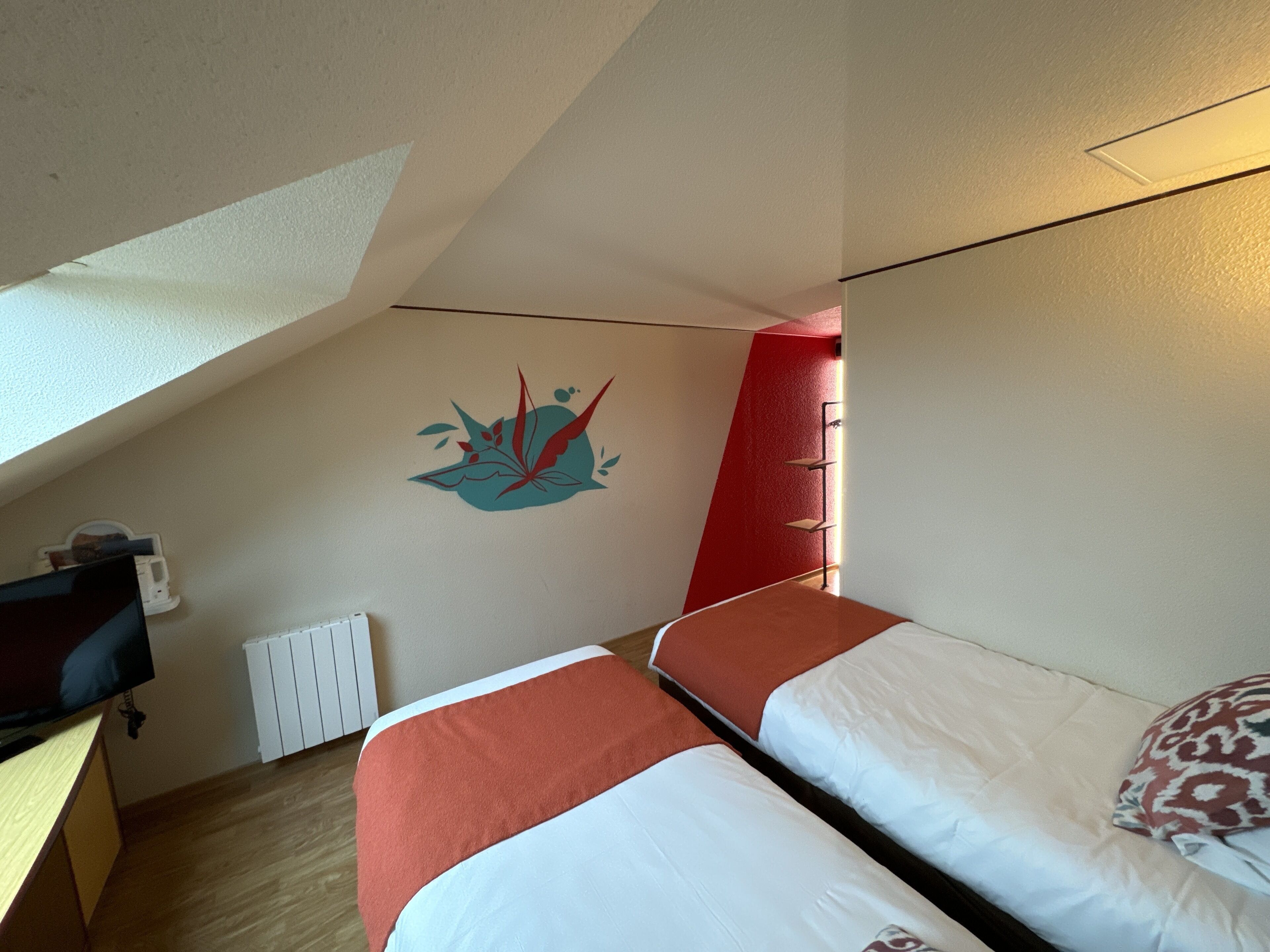 Une chambre avec deux lits, un bureau et un radiateur.