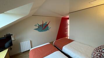 Une chambre avec deux lits, un bureau et un radiateur.