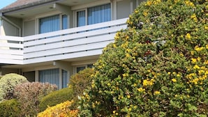 A multi-story building with a balcony, surrounded by well-maintained bushes and trees. - The Originals City - Hotel Restaurant A Pic (Cherbourg-en-Cotentin)