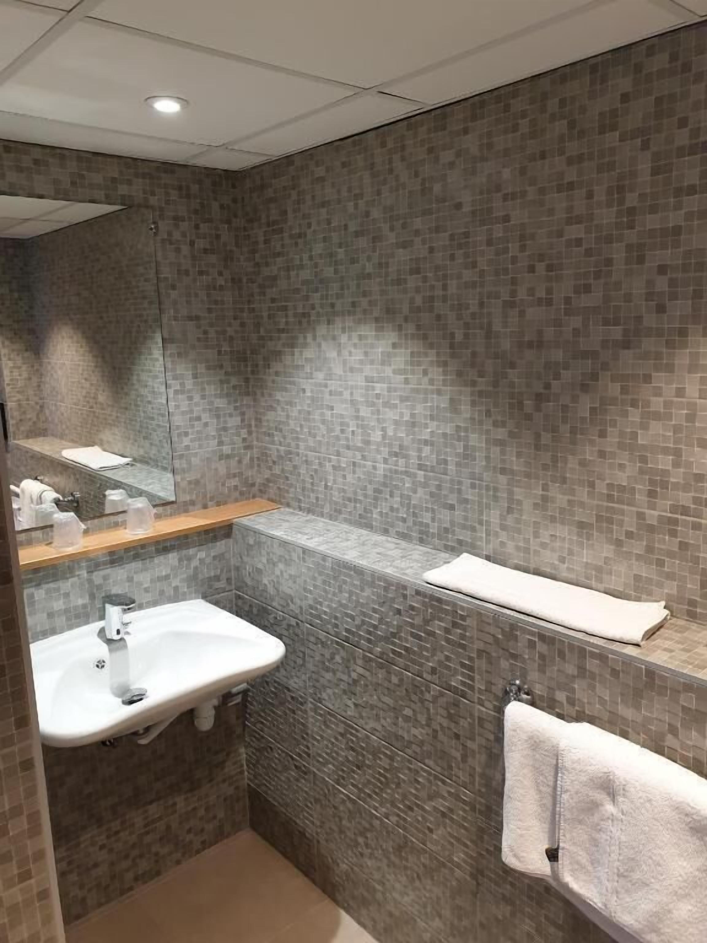 A modern bathroom with a rectangular sink, a mirror, and a towel rack.