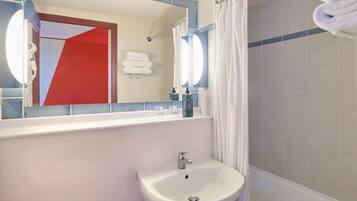 Une salle de bain avec un lavabo blanc, un miroir et un rideau de douche.