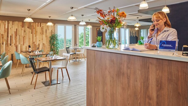 A modern reception area with wooden panel walls, multiple tables and chairs, and hanging pendant lights. - The Originals City - Hotel Restaurant A Pic (Cherbourg-en-Cotentin)