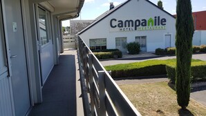 Un hotel chiamato Campanile con un balcone, un vialetto lastricato e un prato ben curato.