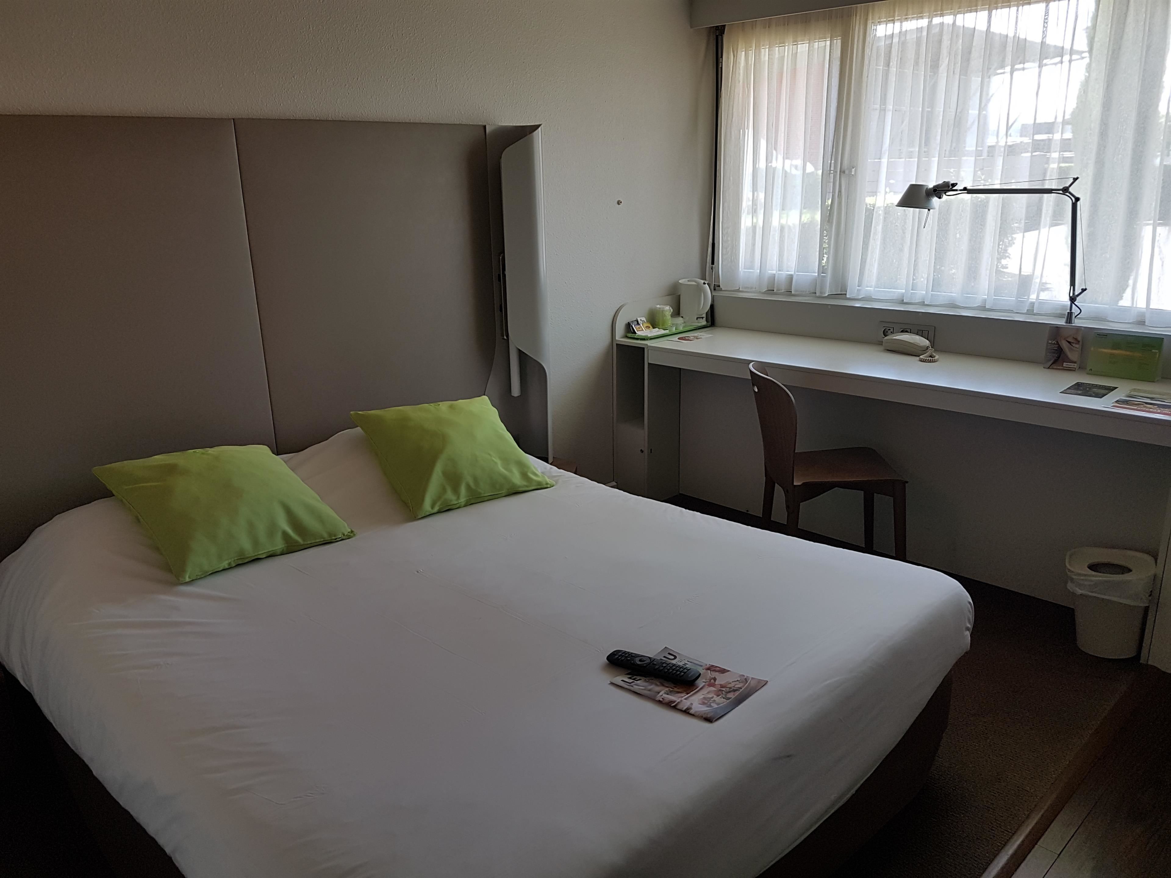 Une chambre d’hôtel avec un lit, un bureau et une fenêtre.