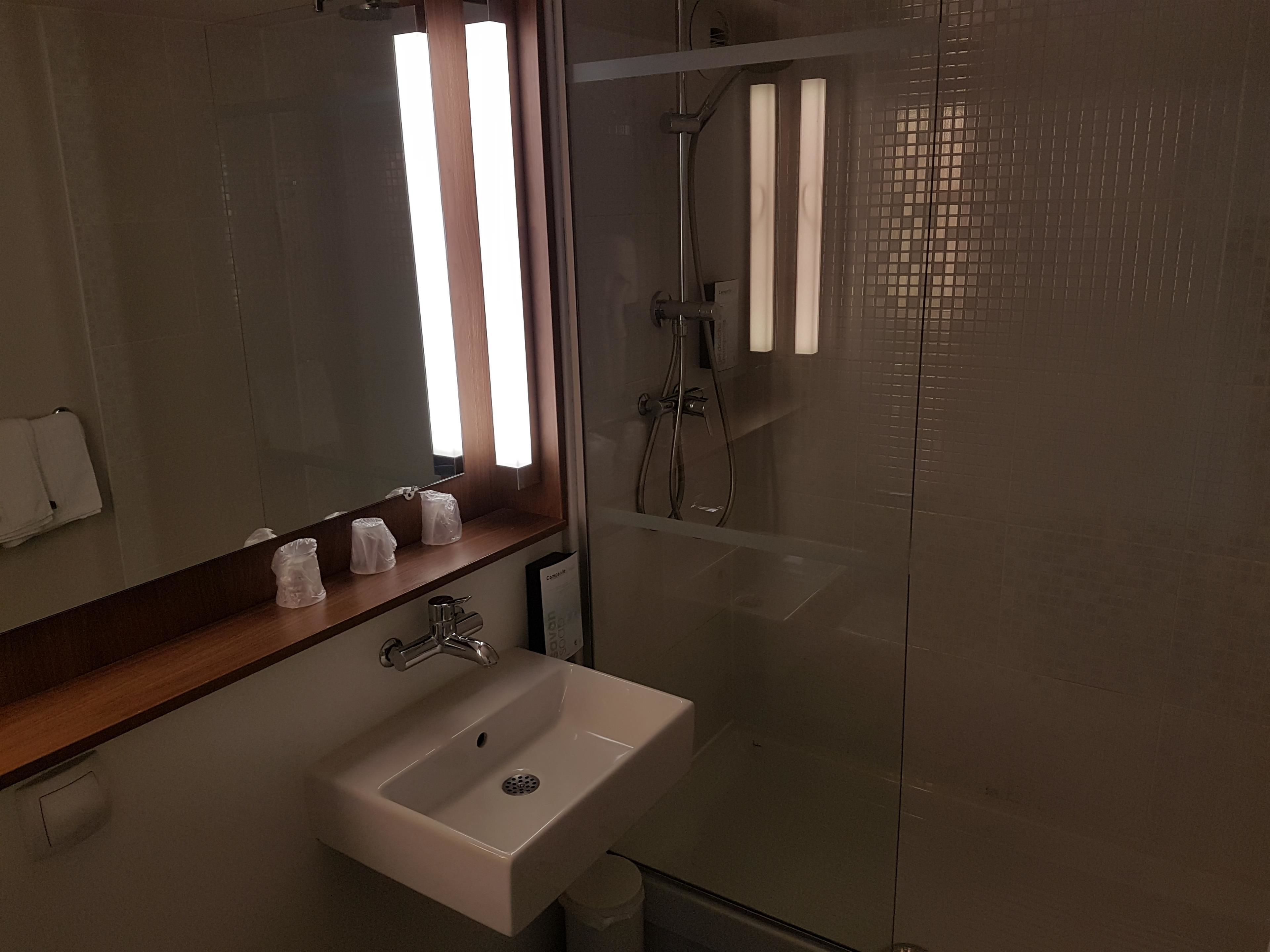 A bathroom with a sink, mirror, and shower.