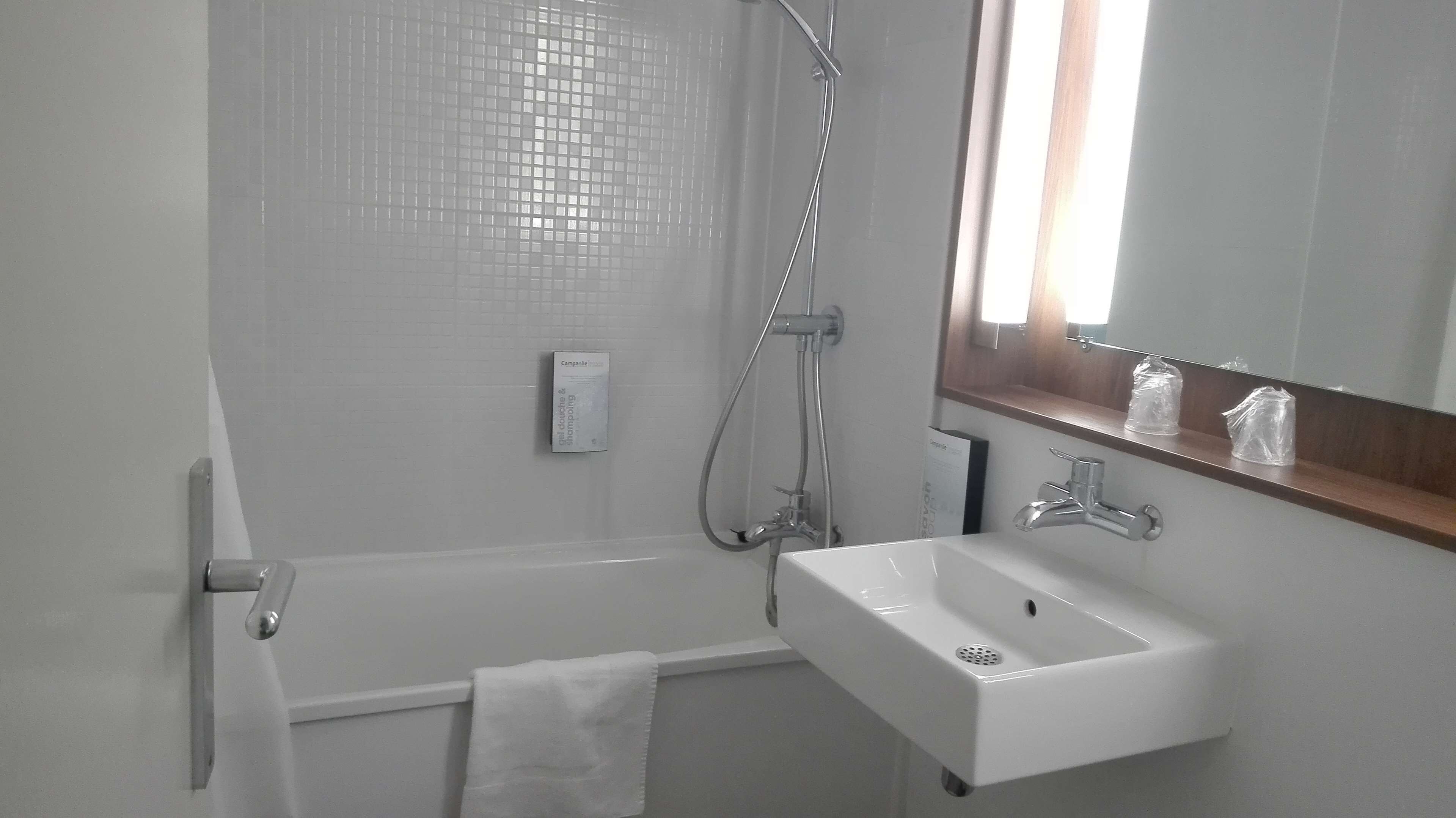 Een moderne badkamer met een witte wastafel, spiegel en douche.